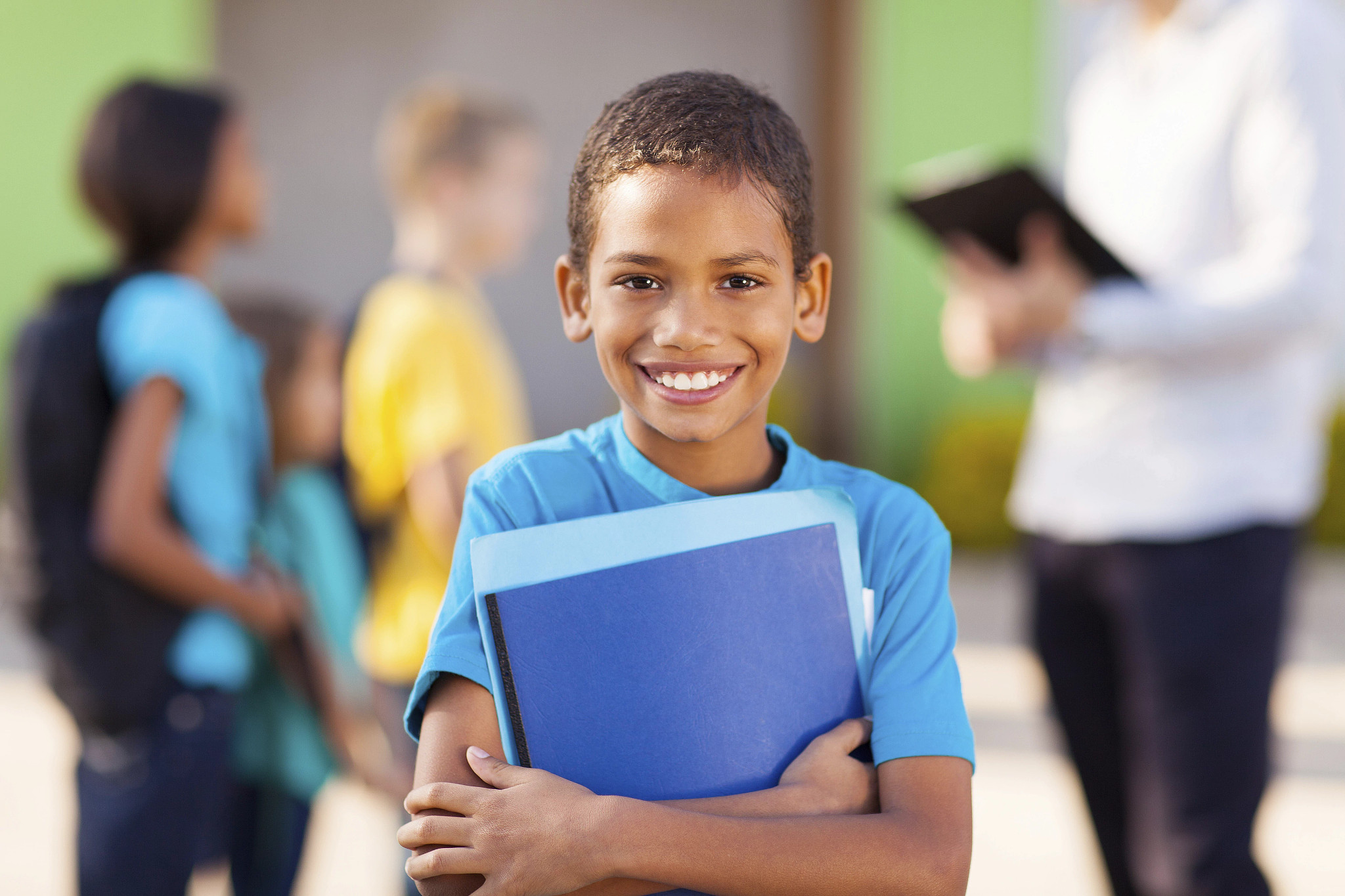 Student holding book in front of school