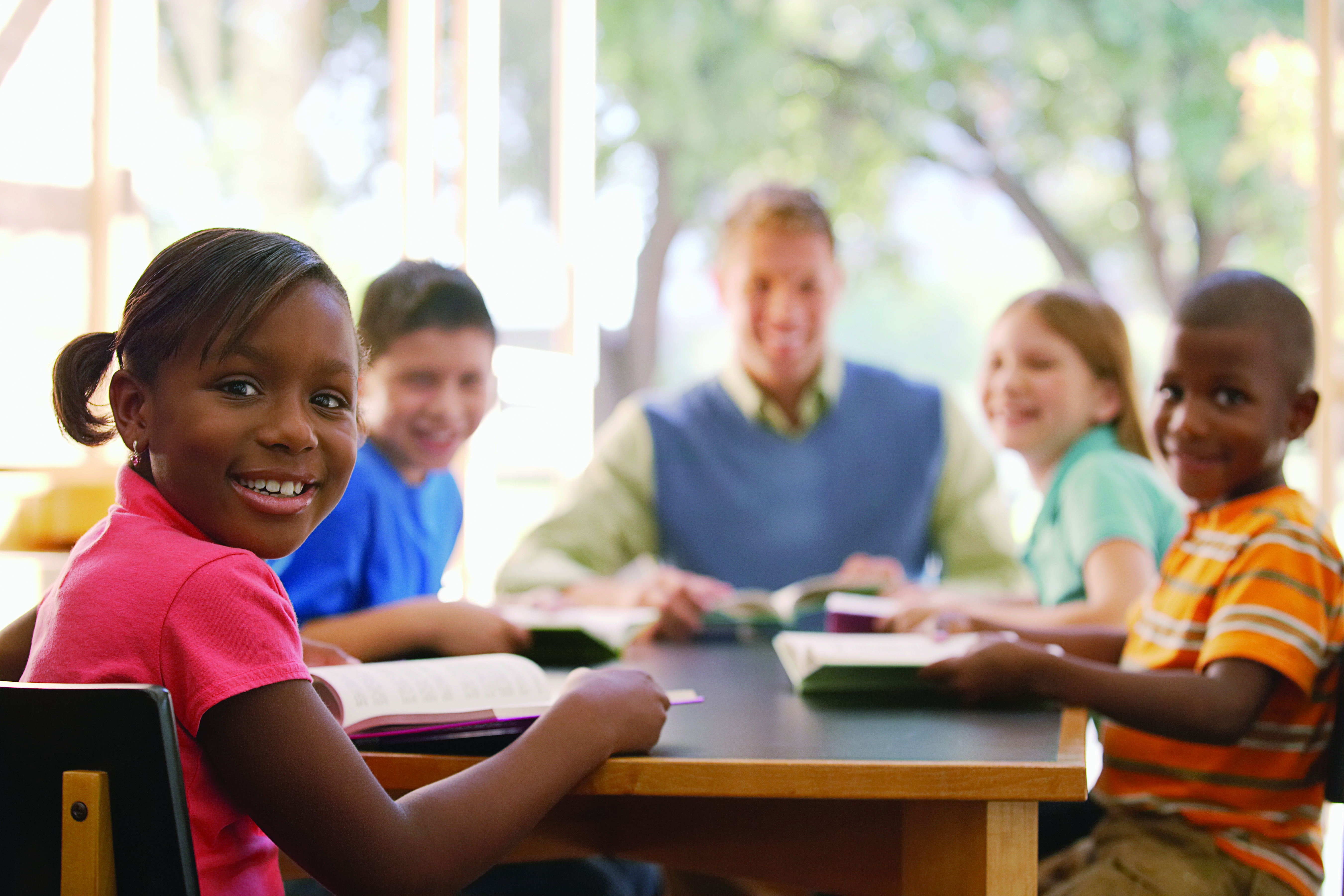 Students at table smiling with teacher