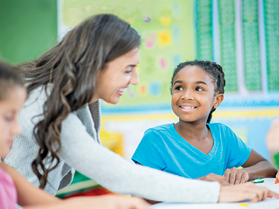 Teacher and student smiling at desk